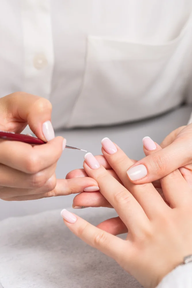 Woman receiving french manicure by beautician