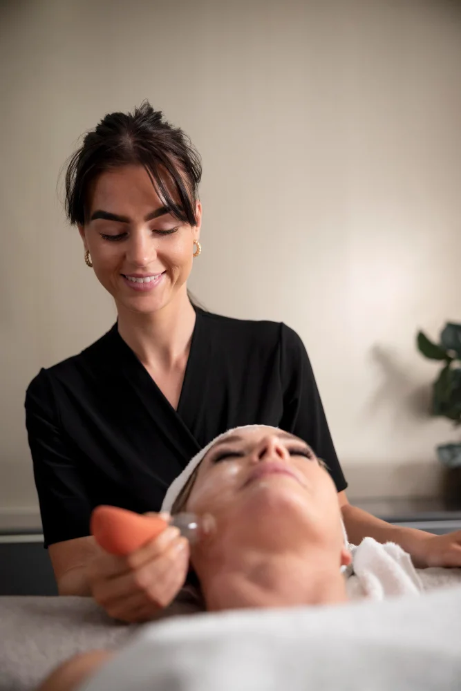 Young woman using a face treatment on her client